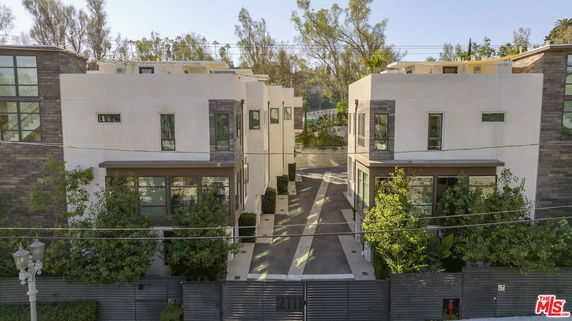 Front view of two modern multi-story buildings with large windows and a shared driveway.