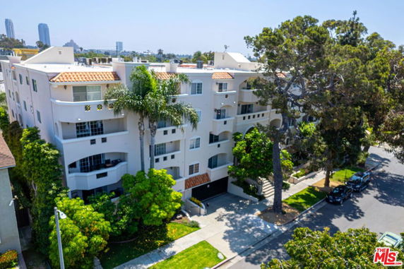 Front view of a multi-story residential building with balconies and a tiled roof.