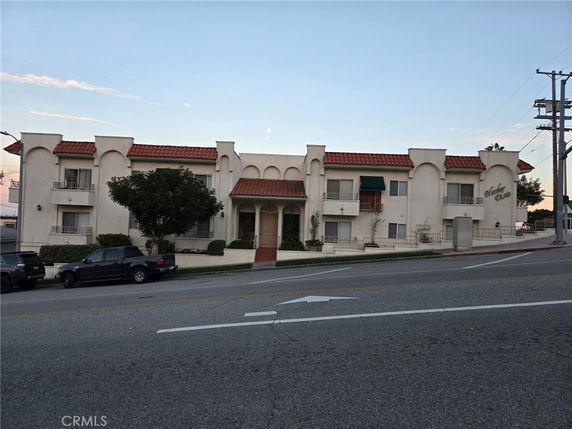 Front view of a two-story building with a red tiled roof and arched features.