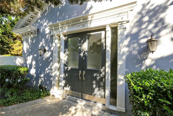 Front view of a house entrance with double doors and decorative trim.