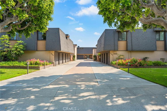 Front view of a residential complex with modern design, featuring a central pathway and garages on either side.