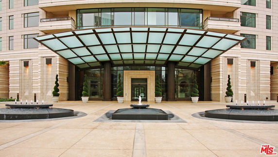 Front view of a modern building with a glass canopy and decorative fountains.