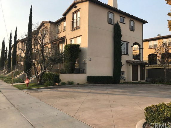 Front view of a multi-story residential building with trees along the sidewalk.