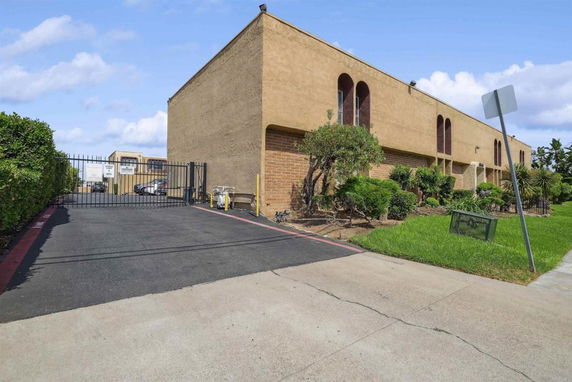 Front view of a two-story building with gated entrance and arched windows.