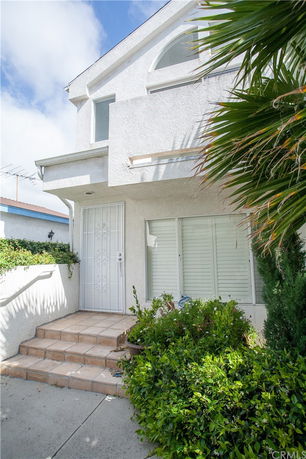 Front view of a two-story house with white exterior and small entrance steps.