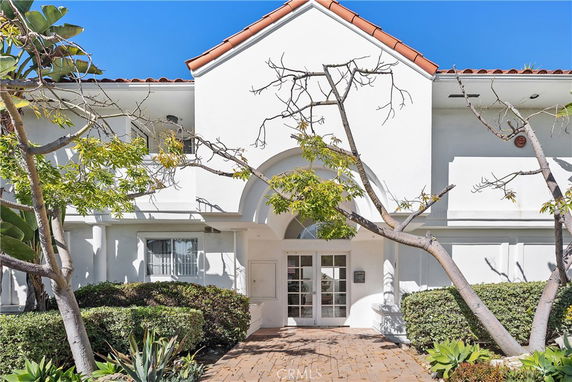 Front view of a two-story building with a white exterior and an arched entrance.