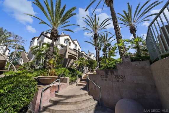 Front view of a multi-story building with palm trees and landscaped stairs.