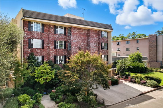 Front view of a multi-story brick apartment building with black window shutters.