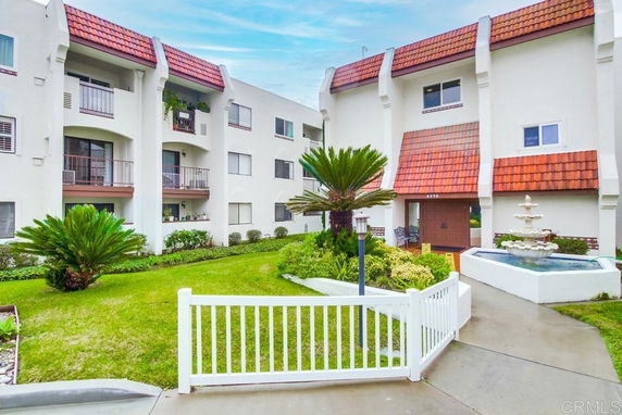 Front view of a multi-story apartment building with balconies and red roof tiles.