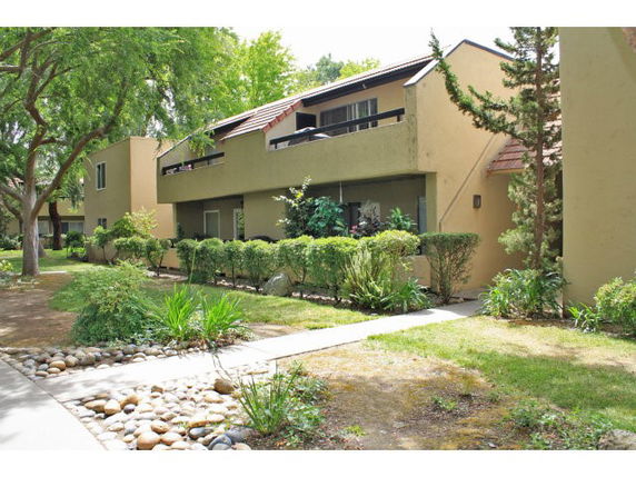 Front view of a multi-story building with balconies and a landscaped garden.