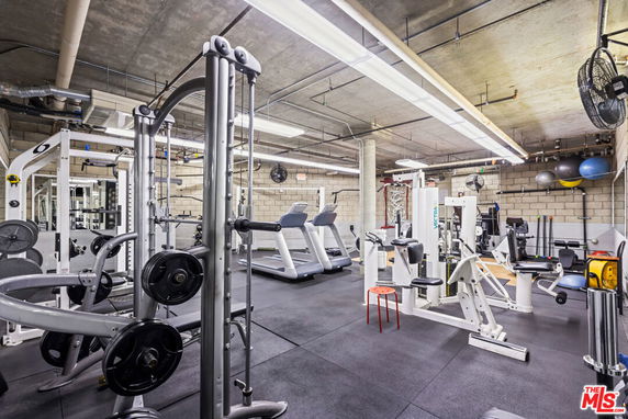 Gym area with exercise equipment including treadmills and weight machines.