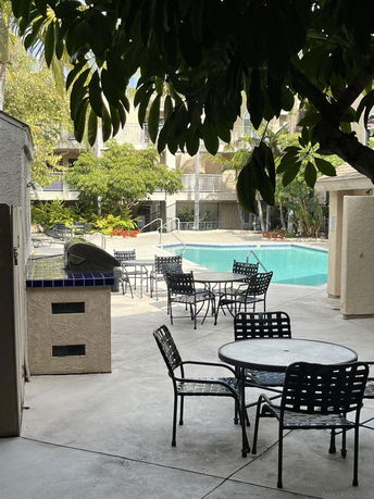 Outdoor area with a swimming pool, surrounded by patio furniture and trees.