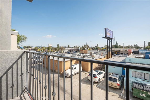 View from a balcony showing nearby buildings, parking area, and a billboard.