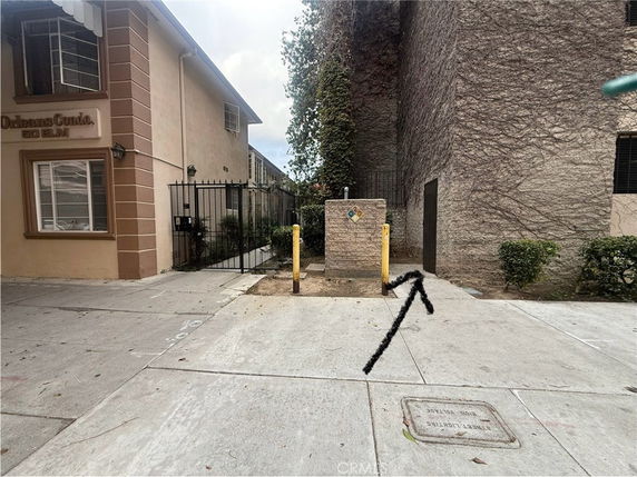 Front view of a two-story building with a gated entrance and a utility area at the front.
