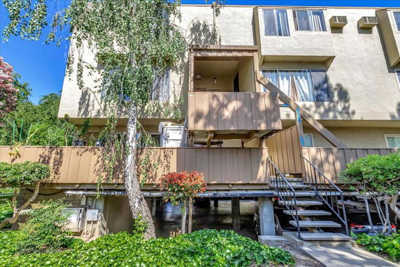 Front view of a multi-story residential building with balconies and exterior stairs.