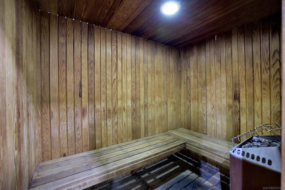 Interior view of a wooden sauna room with benches and a heater.