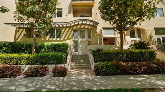 Front view of a multi-story building with stairs leading to an entrance.