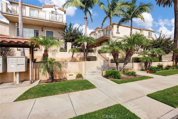 Front view of a multi-story building with balconies and palm trees.