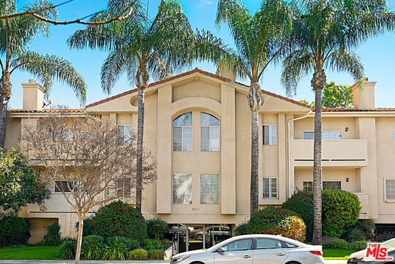 Front view of a multi-story residential building with balconies and palm trees.