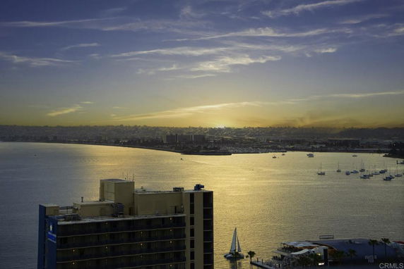 Panoramic view of a waterfront with buildings and boats during sunset.