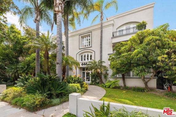 Front view of a multi-story house with large windows and palm trees.