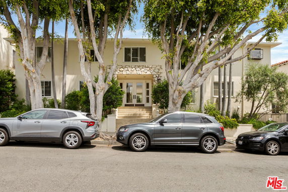 Front view of a two-story house with multiple vehicles parked in front.