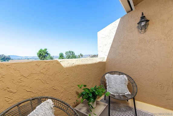 Balcony view with chairs and surrounding landscape visible.