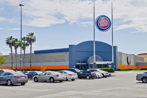 Front view of a large commercial building with a prominent sign and parking lot.
