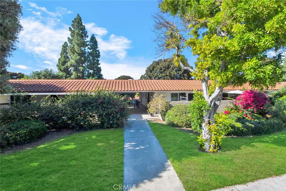 Front view of a single-story house with a tiled roof and surrounding greenery.