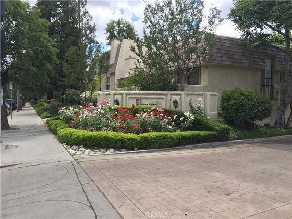 Front view of a building with a garden and boundary wall.