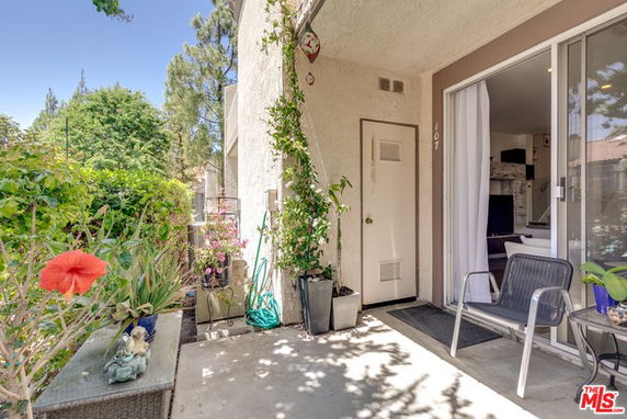 Front view of a house entrance with plants and a small outdoor seating area.