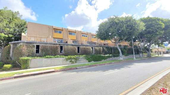 Front view of a multi-story building with a flat roof and several units.