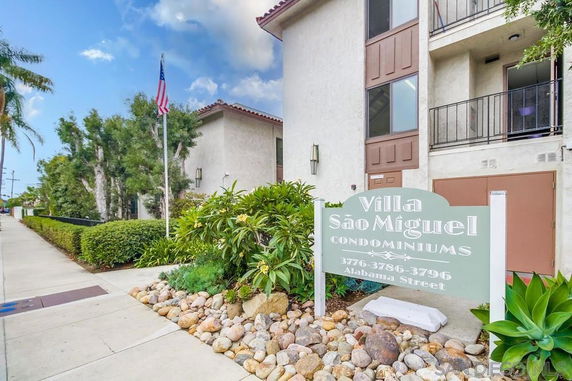 Front view of a condominium building with balconies and a sign reading Villa São Miguel Condominiums.