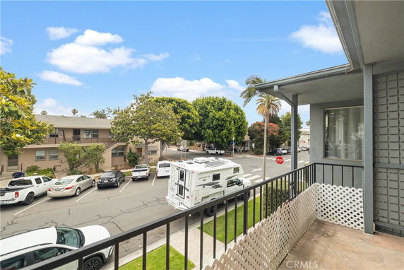 View from the balcony showing a street with parked cars and trees.