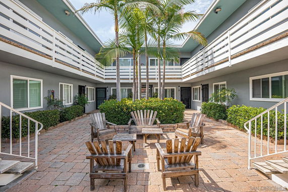 Courtyard view of a residential building with balconies and outdoor seating area.