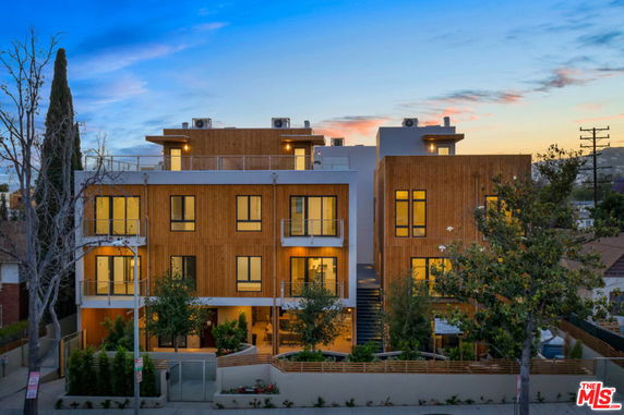 Front view of a modern multi-story building with wood paneling and multiple balconies.