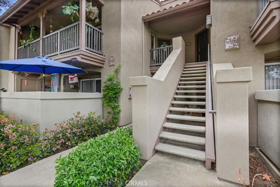Front view of a building with stairs leading to the entrance and a small patio area.