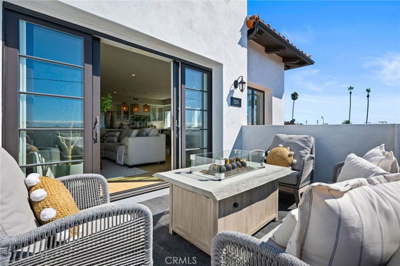 Rooftop terrace with outdoor seating and a fire table, connected to an indoor living area through sliding glass doors.