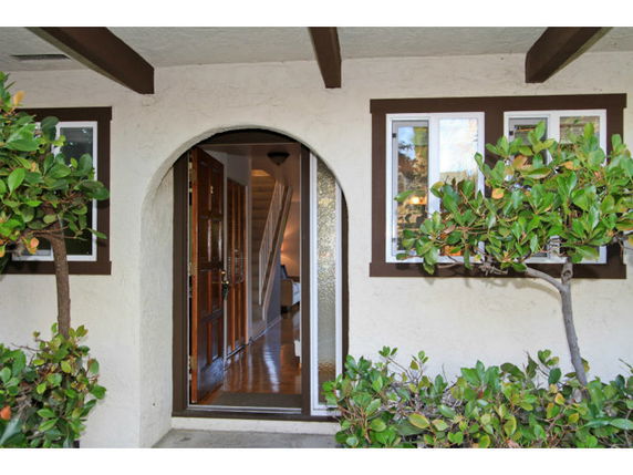 Front entrance of a house with an arched doorway and windows on either side.