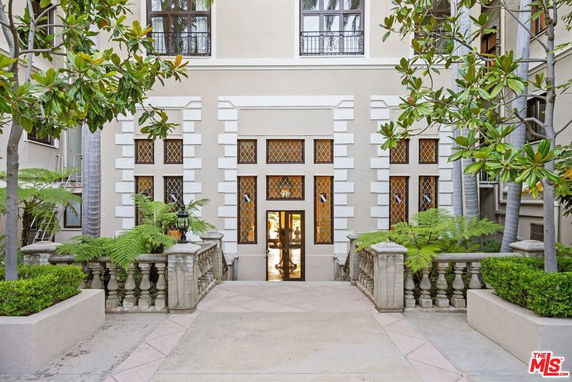 Front view of a building entrance with decorative railing and plants.