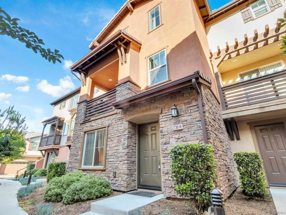 Front view of a multi-story house with a stone facade and balconies.