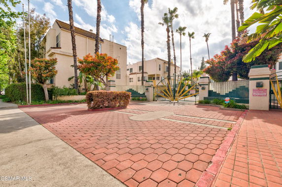 Front view of a residential complex with gated entrance and multi-story buildings.