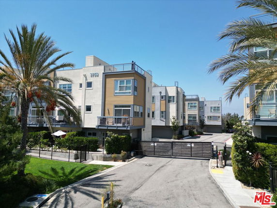 Front view of a multi-story residential building with balconies and a gated entrance.