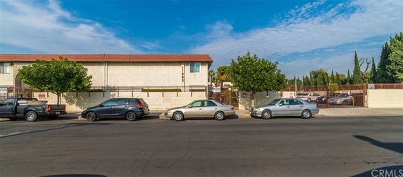 Front view of a two-story building with parked cars on the street.