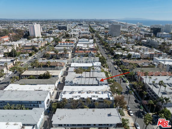 Aerial view of a cityscape with multiple buildings and palm-lined streets.