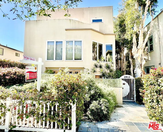 Front view of a multi-story house with large windows and a gated entrance.
