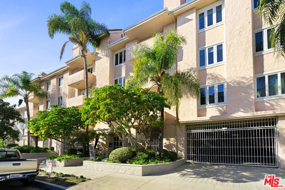 Front view of a multi-story residential building with balconies and gated entrance.