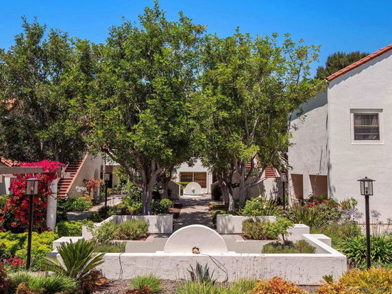Front view of a white two-story building with stairs and a landscaped garden.