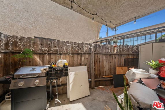 Outdoor patio area with barbecue grill and wooden fence.