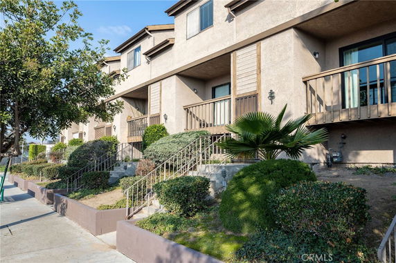 Front view of a multi-story building with balconies and landscaped entrance.